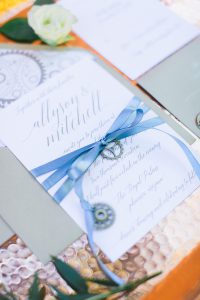A wedding invitation with a blue ribbon