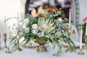 A table centerpiece surrounded by glasses and candles
