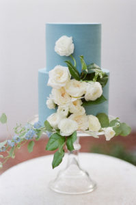 A blue cake with white roses