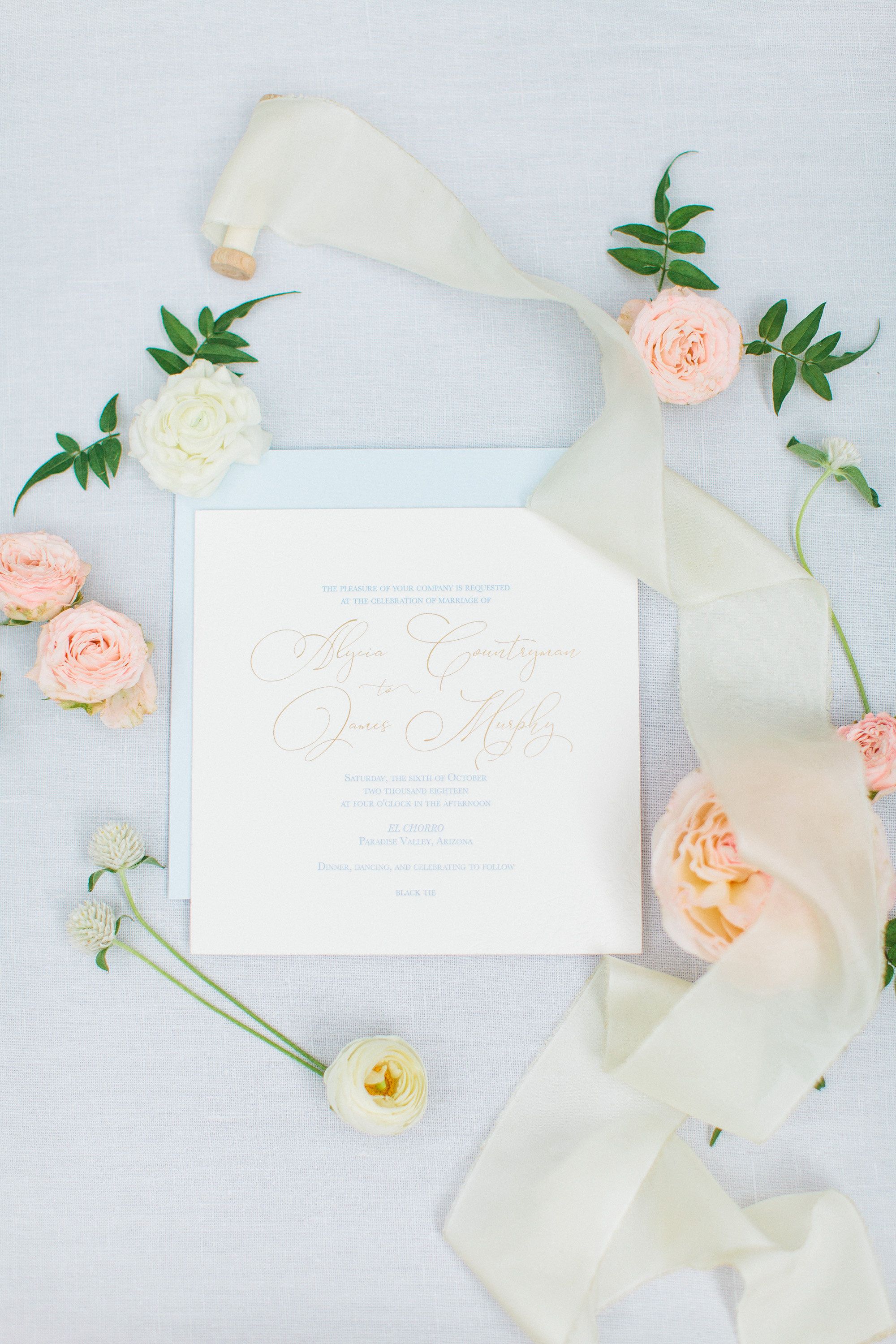 A custom wedding invite surrounded by flowers