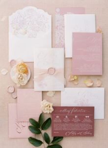 Personalized wedding invitations on a pink surface